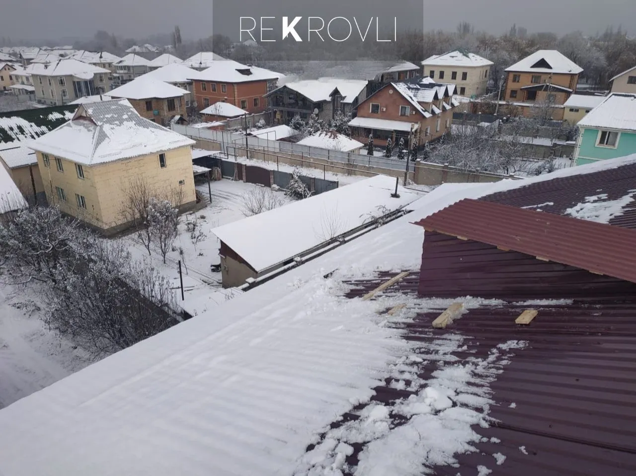 Панорама заснеженного посёлка с крыши, свежесмонтированный бордовый профнастил под снегом