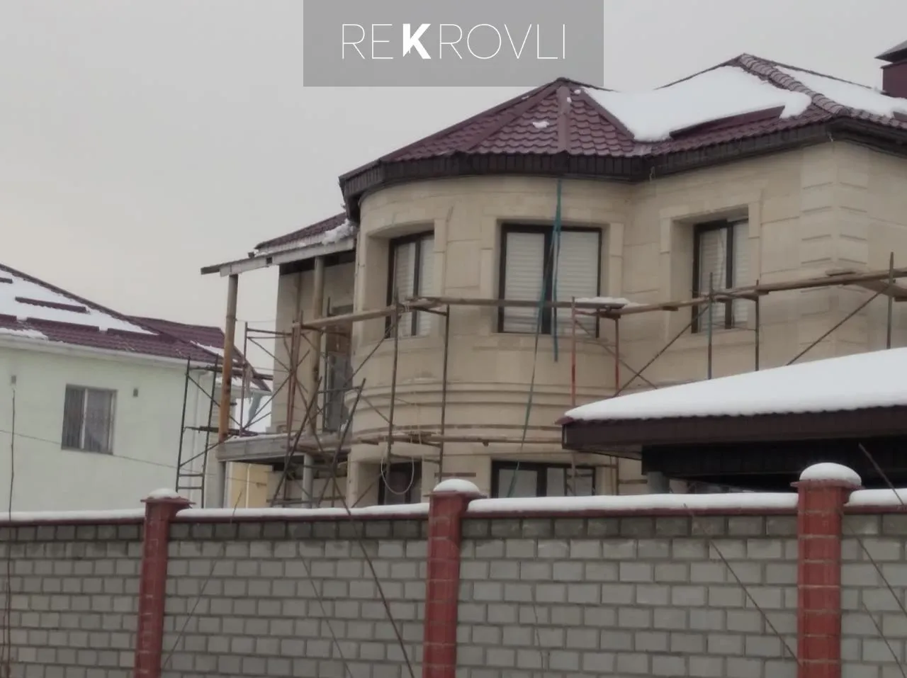 Монтаж металлочерепицы на многоскатной крыше двухэтажного дома в строительных лесах зимой