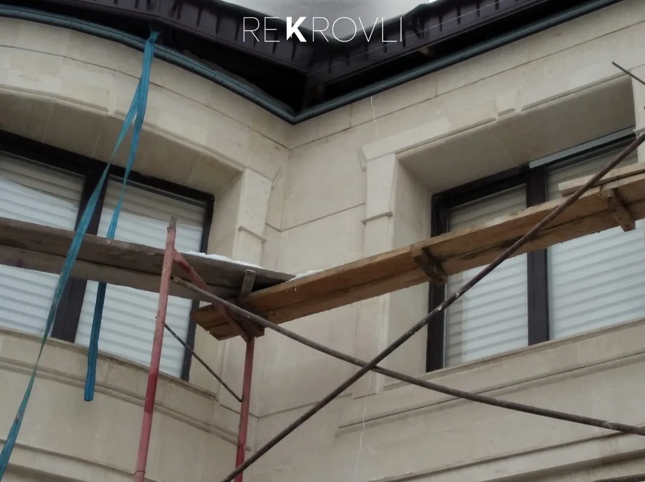 Строительные леса у каменного фасада дома во время кровельных работ