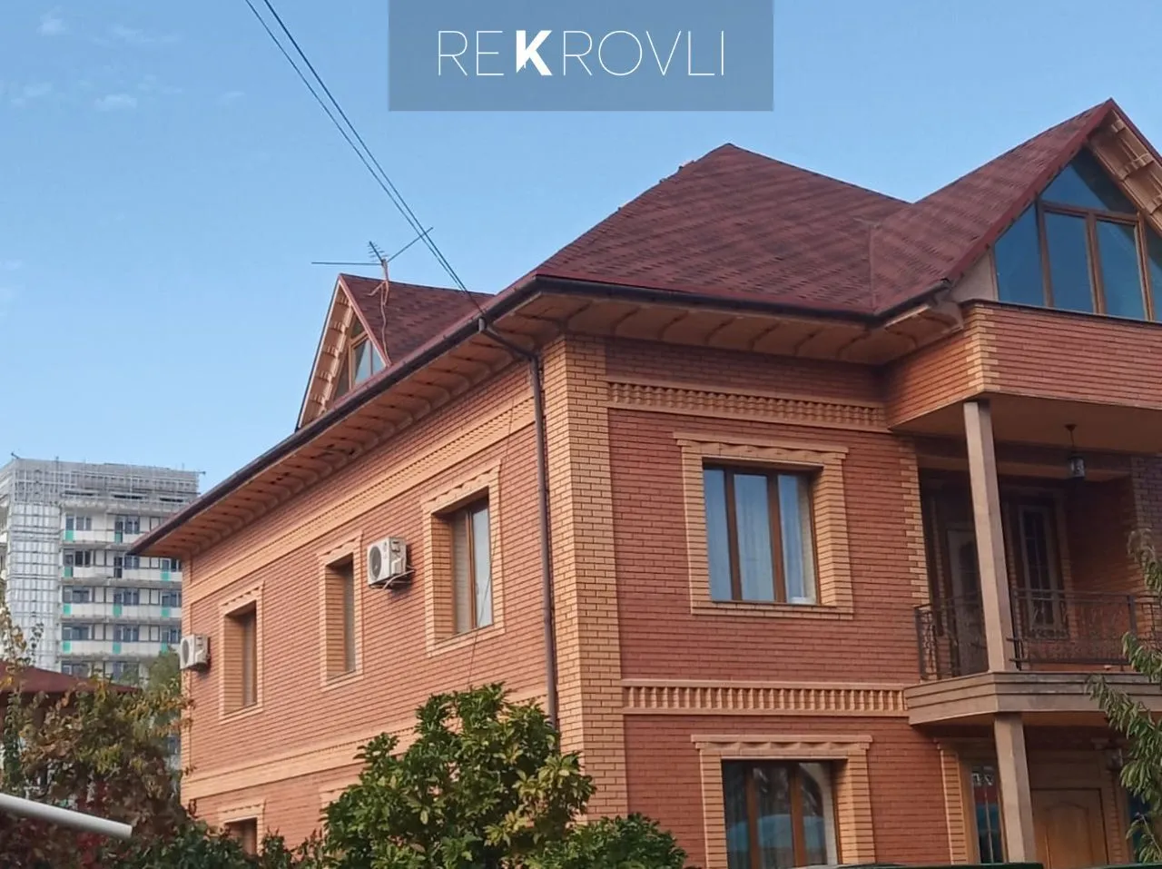 Готовая вальмовая крыша из красной гибкой черепицы на двухэтажном кирпичном коттедже